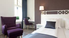 Säng och fåtölj i Superior dubbelrum på Clarion Collection Hotel Grand Gjøvik