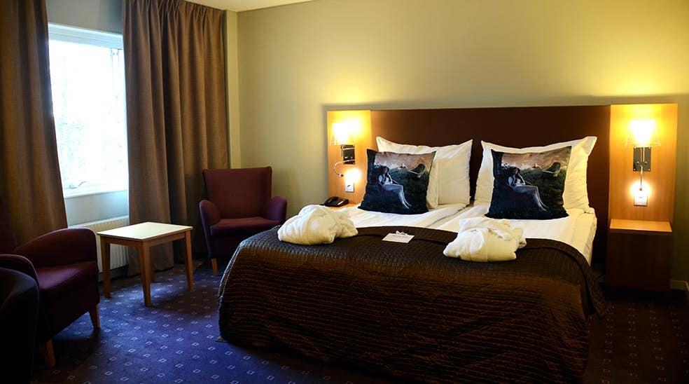 Översikt superiorrum med dubbelsäng, morgonrock, sitthörna och säng på Clarion Collection Hotel Kompaniet Nyköping