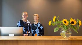 Två glada receptionister i lobbyn på Hotel F6 i Helsingfors, Finland
